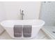 Close up of white soaking tub with gray towels, a faucet, and patterned tile in glass shower enclosure at 1931 Amber Dawn Way, Lawrenceville, GA 30043