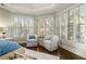 Bright bedroom featuring shuttered windows, hardwood floors, and seating area at 4465 Newhall Dr, Cumming, GA 30040