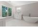 A bright bathroom featuring a white vanity, round mirror, soaking tub and a large window overlooking trees at 304 Trecastle Ln # 28, Canton, GA 30114