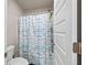 Cozy bathroom with a toilet and a shower featuring a shower curtain with blue stripes at 332 Hinton Farm Way, Dacula, GA 30019