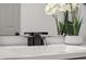 Modern bathroom sink features a sleek black waterfall faucet and is accented with a delicate white orchid at 7256 Attache Way, Riverdale, GA 30296