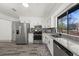 Bright kitchen with stainless steel appliances, white cabinets, and gray wood-style flooring at 7256 Attache Way, Riverdale, GA 30296