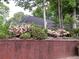 Home exterior featuring a dark gray roof, brick accent wall, and pink flowering bushes at 3620 Highpoint Rd, Cumming, GA 30041