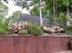 Home exterior with a brick wall, featuring blooming pink azaleas enhancing the landscape at 3620 Highpoint Rd, Cumming, GA 30041