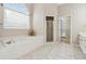 Main bathroom with tiled floors, a bathtub with gold fixtures, a walk-in shower, and a linen closet at 3620 Highpoint Rd, Cumming, GA 30041