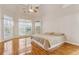Light-filled main bedroom featuring hardwood floors, a ceiling fan, and multiple windows with sheer curtains at 3620 Highpoint Rd, Cumming, GA 30041