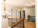 Second floor hallway with decorative chandelier and wooden and black metal railing at 207 Birchwood Dr, Loganville, GA 30052