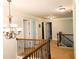 Hallway with chandelier, decorative iron and wood railing, and multiple doors at 207 Birchwood Dr, Loganville, GA 30052