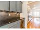 Elegant gray bar area with built-in wine cooler and tiled backsplash leading to a kitchen view at 2629 Apple Valley Ne Rd, Brookhaven, GA 30319