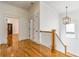 Hallway with hardwood floors, white walls, stairs, and elegant light fixture at 2629 Apple Valley Ne Rd, Brookhaven, GA 30319