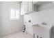 Clean laundry room featuring a white sink, tiled flooring, and window with natural light at 2629 Apple Valley Ne Rd, Brookhaven, GA 30319