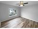 Bright bedroom featuring wood flooring, a ceiling fan, and a large window with neighborhood view at 3519 Cast Palm Dr, Buford, GA 30519