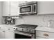 Close-up of the stainless steel oven and stove, microwave and marble backsplash, and modern white cabinets at 4740 Cypress Commons, Atlanta, GA 30338