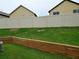 Grassy backyard with wood retaining wall and a white vinyl fence at 2761 Trebek Ct, Mcdonough, GA 30253