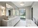 This bathroom features a double vanity, a soaking tub, recessed lighting, and a large window at 100 Tuxedo Nw Ter, Atlanta, GA 30342