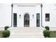 Elegant home entrance featuring a modern arched door, complemented by stone steps and manicured bushes at 100 Tuxedo Nw Ter, Atlanta, GA 30342