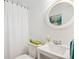 Bathroom with a white sink, toilet, shower with curtain, and a round decorative mirror at 2528 Fernleaf Nw Ct, Atlanta, GA 30318