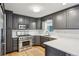 Renovated kitchen featuring gray cabinets, stainless appliances, stone countertops, and tile floors at 2528 Fernleaf Nw Ct, Atlanta, GA 30318