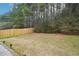 Large backyard with a lawn and a wooden fence with trees in the background at 7717 Bellmist Dr, Fairburn, GA 30213