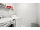 Bright laundry room featuring a modern washer and dryer and ample storage space on the overhead shelving at 7717 Bellmist Dr, Fairburn, GA 30213