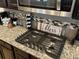 Close-up of a kitchen cooktop featuring granite countertops, stainless steel appliances, and decorative accents at 140 Craines Vw, Covington, GA 30014