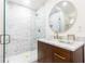 Bathroom featuring stone tiled shower with glass door, wood vanity and round mirror at 2466 Sharondale Ne Dr, Atlanta, GA 30305