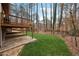 Multi-level backyard with a deck, patio, and lush green lawn with wooded backdrop at 9480 Hillside Dr, Roswell, GA 30076