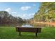 Bench overlooks a calm lake surrounded by trees, offering a serene setting and lush greenery at 9480 Hillside Dr, Roswell, GA 30076