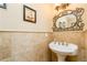 Elegant half bathroom with marble tiles, a pedestal sink, and stylish decorative mirror at 271 Double Gate Ct, Sugar Hill, GA 30518