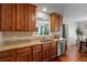 Kitchen featuring wooden cabinets, granite countertops, stainless steel dishwasher, and tile backsplash at 2773 Saddle Horn Place Southwest Pl, Snellville, GA 30039