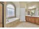 Bathroom features soaking tub under stained-glass window, wood vanity with large mirror, and tile flooring at 2740 Heritage Bend Ct, Grayson, GA 30017