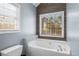 Bathroom showcasing a soaking tub next to the toilet and a view from two windows at 50 Berkshire Run, Covington, GA 30016