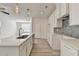 Well-lit kitchen with white cabinets, island with sink, stone countertops, and view into the living area at 2761 Sandy Rd, Conyers, GA 30013