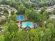 Aerial view featuring a community pool, tennis courts, lush greenery, and clubhouse surrounded by mature trees at 1430 Watercove Ln, Lawrenceville, GA 30043