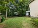 Large backyard surrounded by mature trees, showing lush green grass, wooden planters and a view of the home's exterior at 1430 Watercove Ln, Lawrenceville, GA 30043