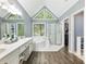 Well-lit bathroom with a double sink vanity, a shower, and a large tub under triangular windows at 1430 Watercove Ln, Lawrenceville, GA 30043