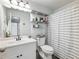 Bright bathroom with a white vanity, floating shelves, and a shower with a striped curtain at 1430 Watercove Ln, Lawrenceville, GA 30043