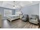 Spacious main bedroom featuring a tray ceiling, fan, light blue walls, and sitting area at 1430 Watercove Ln, Lawrenceville, GA 30043