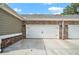 Attached two-car garage featuring traditional white doors, brick accents and stylish exterior lighting at 3901 Shelleydale Dr, Powder Springs, GA 30127