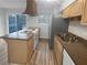 Well-lit kitchen featuring a stove, stainless steel fridge, wooden cabinets, and island with sink at 3085 Colonial Way # G, Atlanta, GA 30341