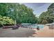 Community pool surrounded by a fence, lounge chairs, tables, umbrellas, and lush greenery at 3085 Colonial Way # G, Atlanta, GA 30341