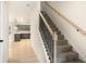 Carpeted staircase with black metal spindles and wood handrail, providing a modern transition to the upper level and kitchen view at 735 Shetland Trl, Cartersville, GA 30121