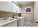 Laundry room includes white cabinets, tile floors, sink, and washer and dryer at 857 Stovall Ne Pl, Atlanta, GA 30342