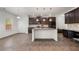 Open concept kitchen featuring an island, dark cabinets, stainless steel appliances and wood floors at 1390 Napa Valley Sw Dr, Lawrenceville, GA 30045