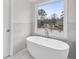 Bright bathroom with freestanding tub, marble accents and natural light from a large window with neighborhood views at 5115 N Pratt St, Covington, GA 30014