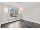 Bedroom with a large window offering neighborhood views, complemented by elegant lighting fixtures and hardwood flooring at 5115 N Pratt St, Covington, GA 30014