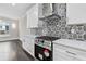 Kitchen featuring stainless steel stove, white cabinets, quartz countertops, and modern tiled backsplash at 5115 N Pratt St, Covington, GA 30014