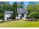 Beautiful white home with a black roof, surrounded by lush greenery and a well-manicured lawn at 11260 Houze Rd, Roswell, GA 30076