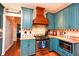 Stylish kitchen with teal cabinets, stainless steel oven, custom vent hood, and tile backsplash at 190 Country Club Dr, Hiram, GA 30141