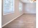 A spacious living room with wood-look floors, two windows, and a ceiling fan with lights at 8904 Creekwood Ct, Riverdale, GA 30274